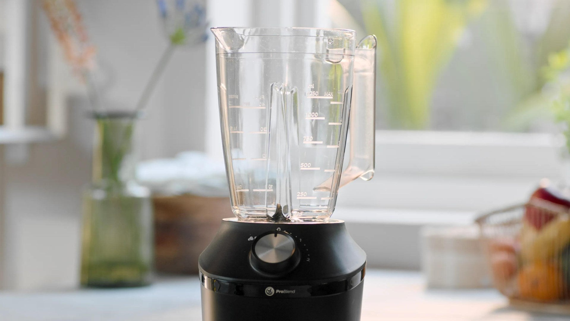 Una licuadora moderna y vacía con jarra transparente y base negra se encuentra en la cocina.