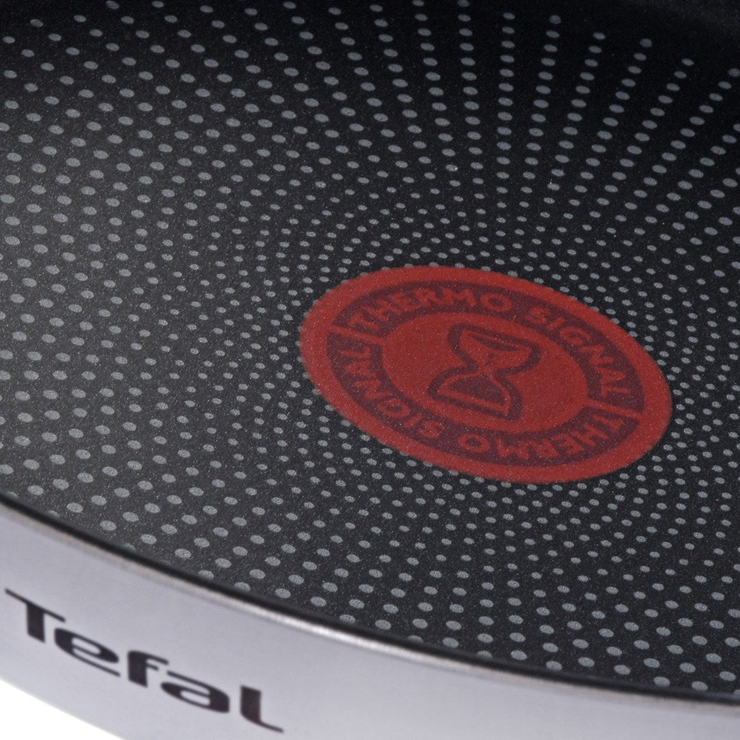 Close-up of a black non-stick coating on a Tefal pan with a red Thermo-Signal in the center.