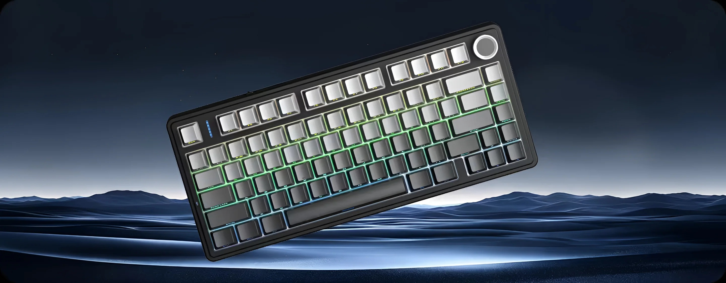 Czarna klawiatura z podświetleniem RGB unosi się przed niebieskim górzystym krajobrazem.