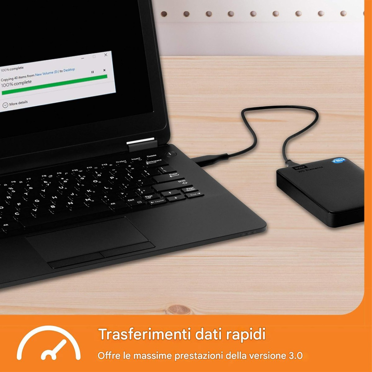 Un computer portatile nero su un tavolo di legno, collegato con un cavo a un disco rigido esterno.