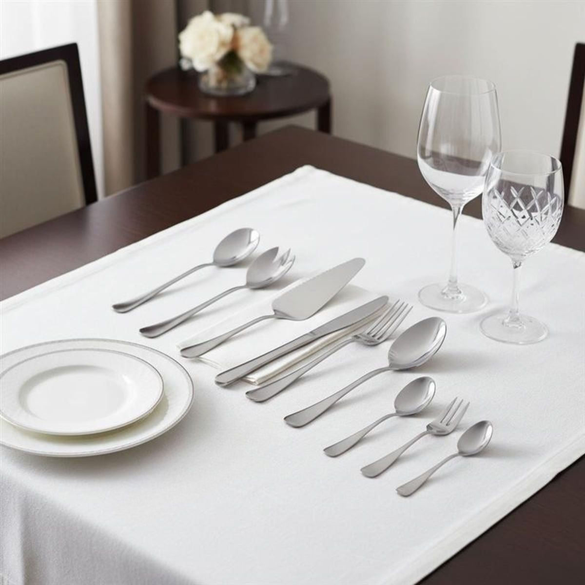 Ein eleganter Tisch mit Geschirr, Besteck und Gläsern auf einer weißen Tischdecke.