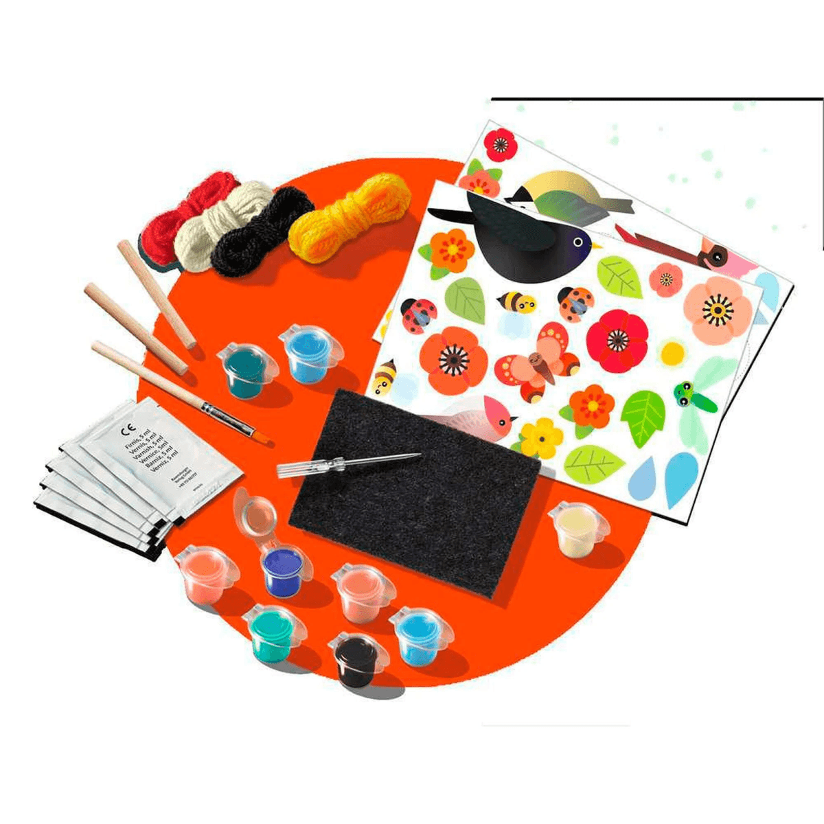Ein Bastelset mit bunten Farben, Pinseln, Garn, Stickvorlagen und Aufklebern auf rotem und weißem Untergrund.