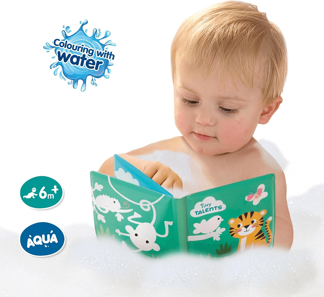 Niño pequeño sentado en un baño de espuma, mirando un libro ilustrado verde.