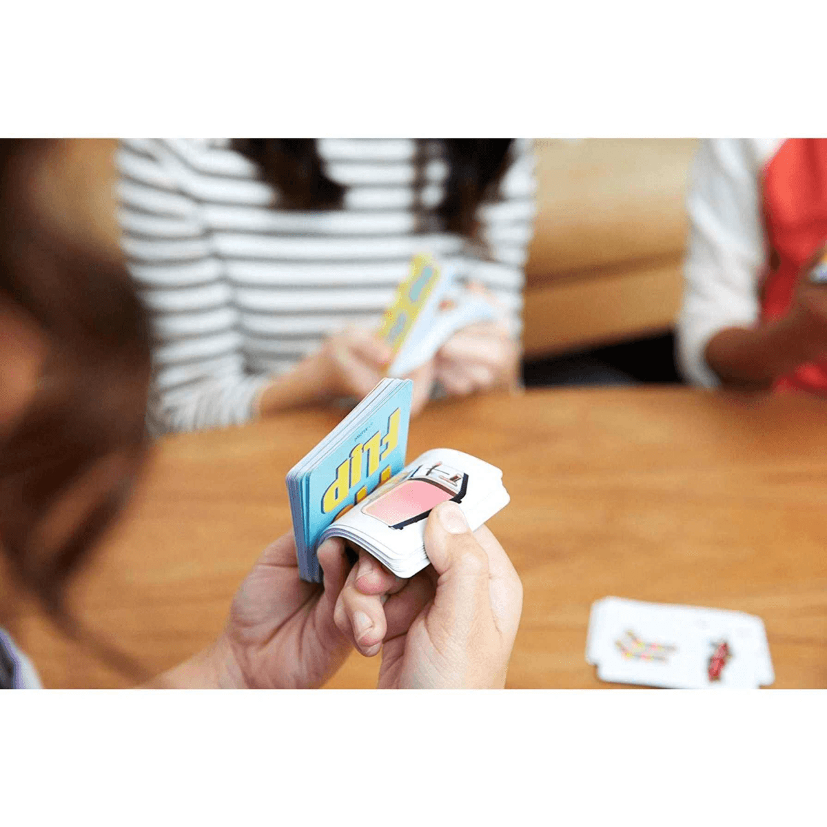 Personas se sientan en una mesa de madera sosteniendo cartas.