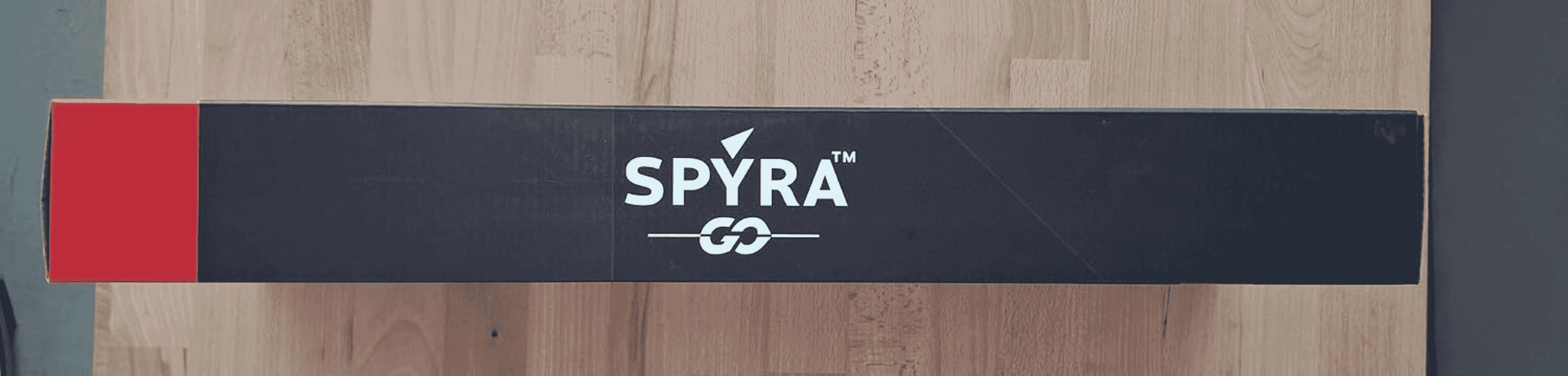 Una caja negra de SpyraGo con texto blanco sobre una superficie de madera.
