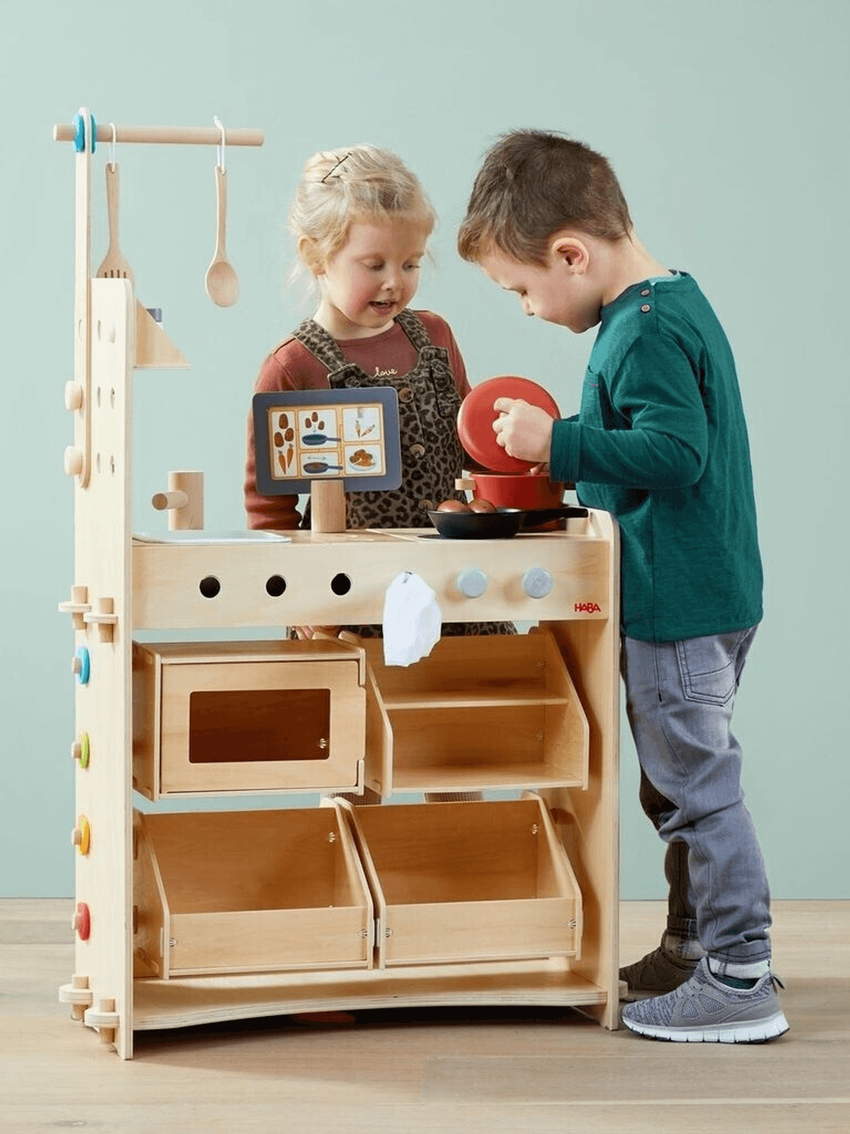 Ein Junge und ein Mädchen spielen zusammen an einer Holzküche.