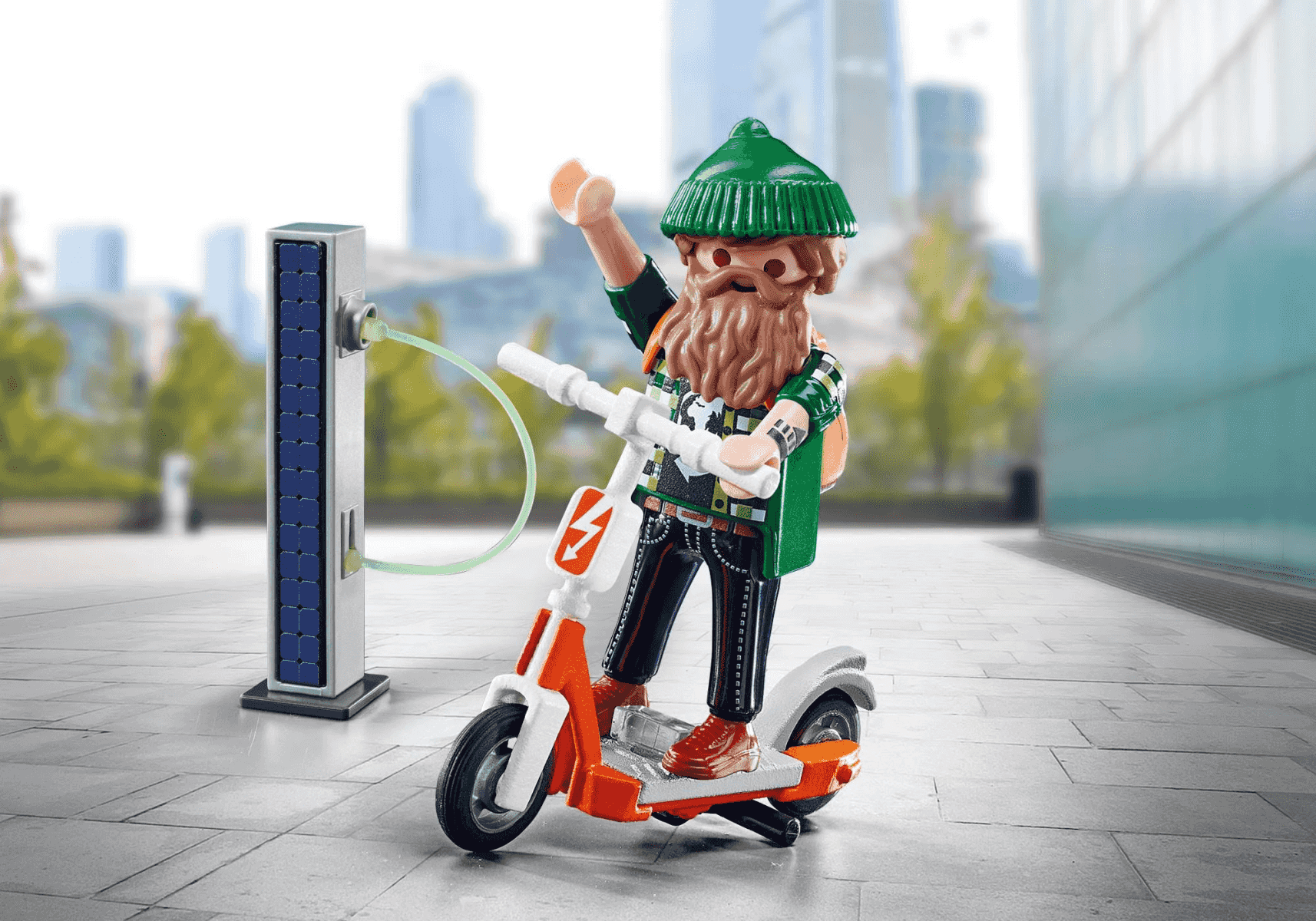 Playmobil-Figur mit Bart und grüner Mütze fährt E-Scooter an einer Solar-Ladestation vor einer Stadt.