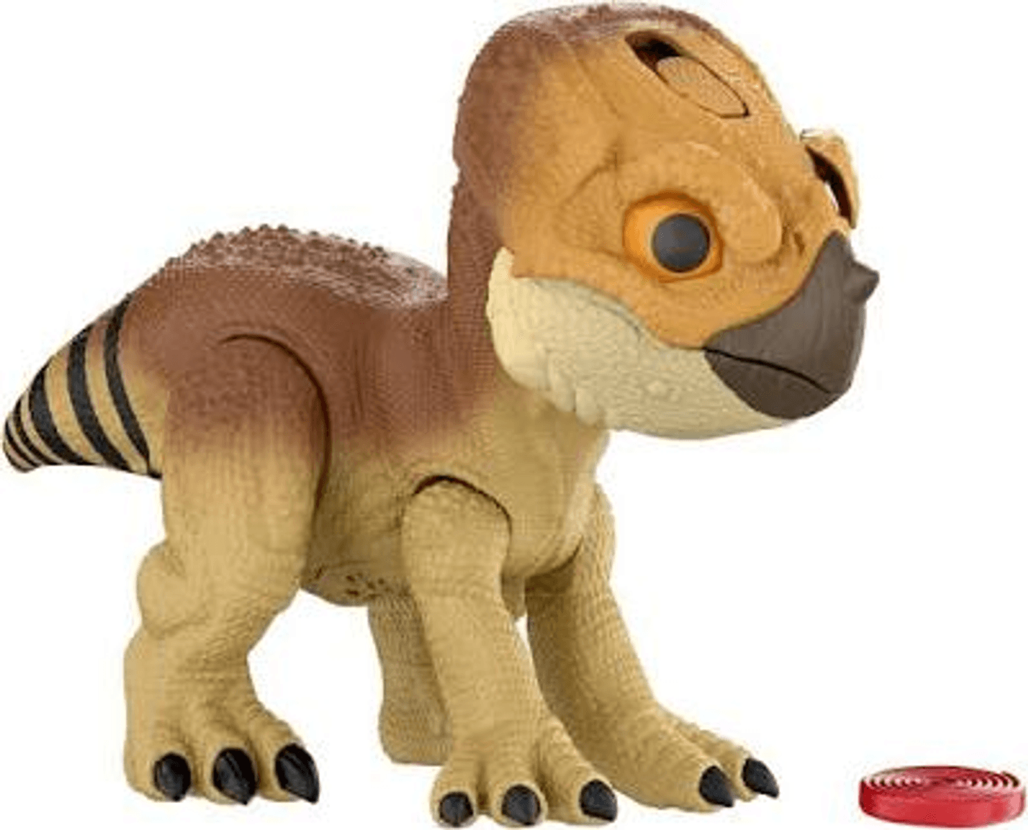 Un juguete de dinosaurio bebé marrón con grandes ojos naranjas se encuentra junto a un pequeño objeto rojo sobre fondo blanco.