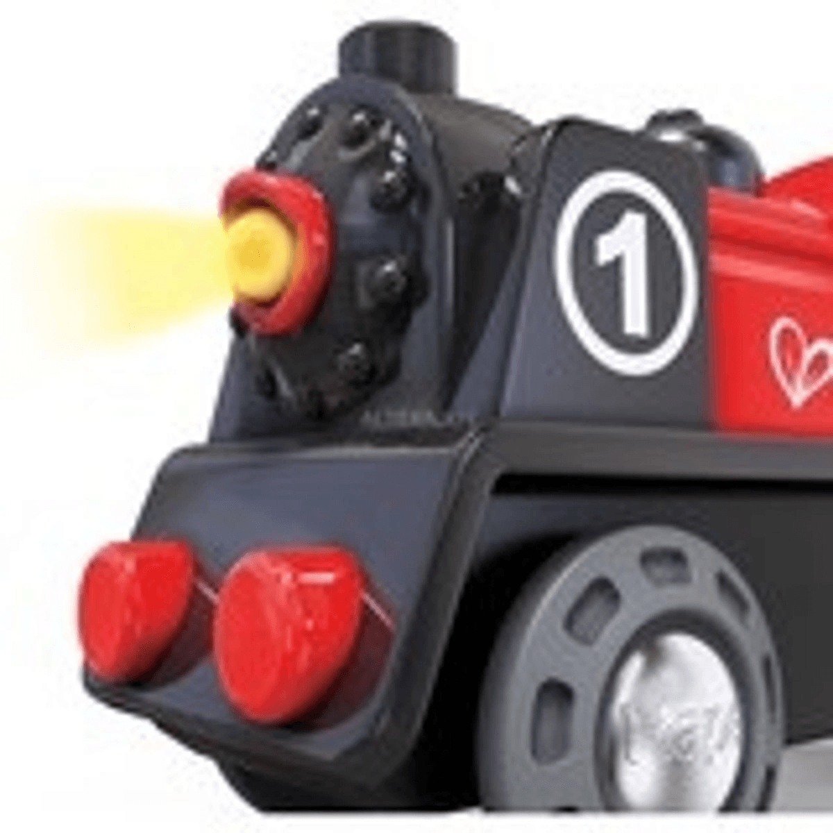 Primer plano de un tren de juguete a vapor negro y rojo con el número uno en el lateral y un faro amarillo brillante.