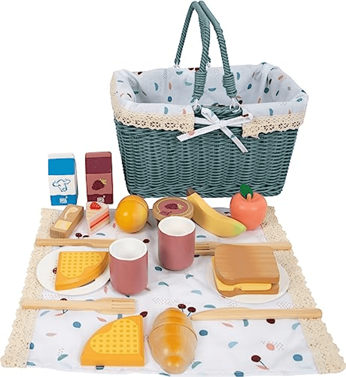 Una cesta de mimbre verde con forro de tela detrás de una manta de picnic con juguetes de madera como fruta, gofres y menaje.