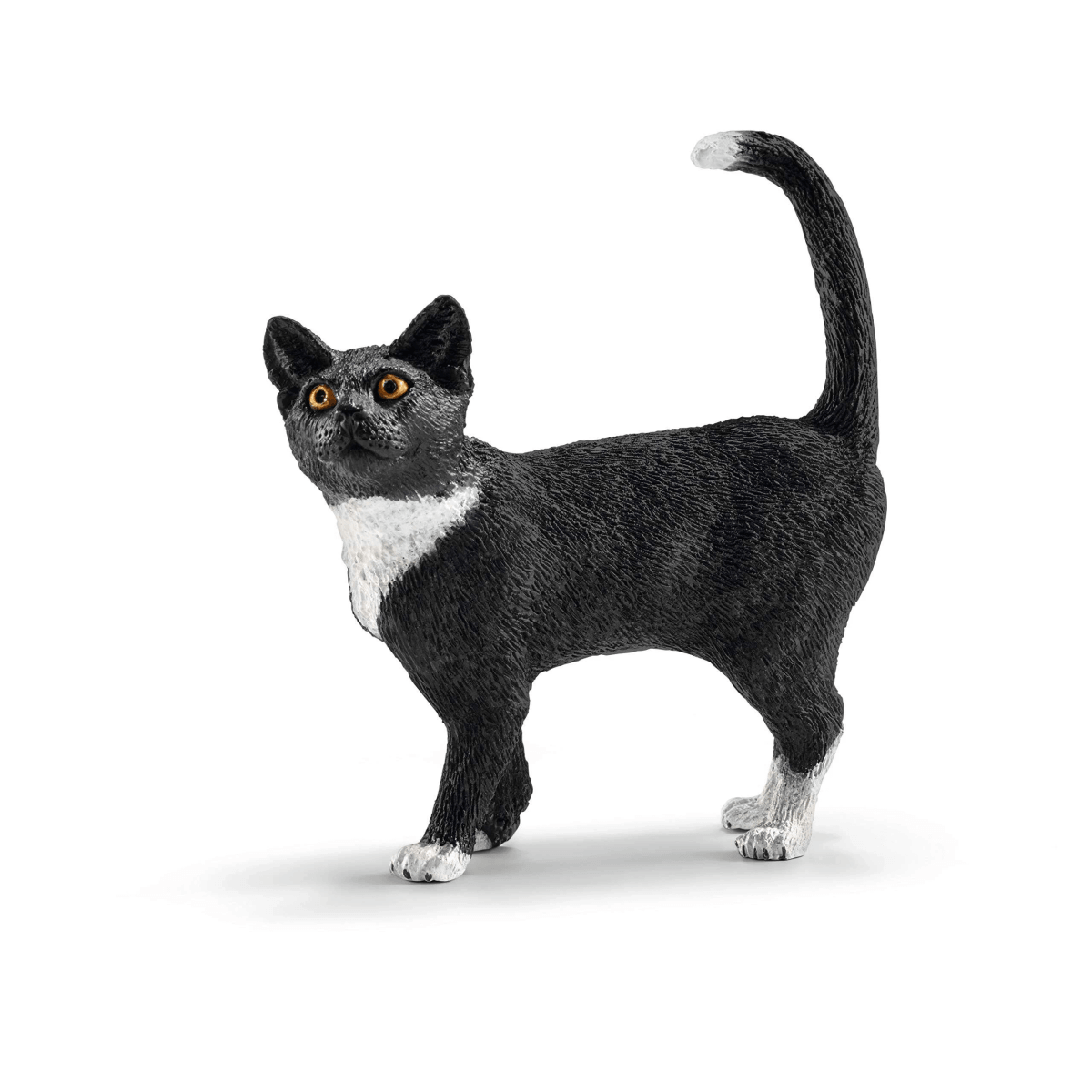 Una figura de juguete de un gato blanco y negro con la cola curvada hacia arriba sobre fondo blanco.