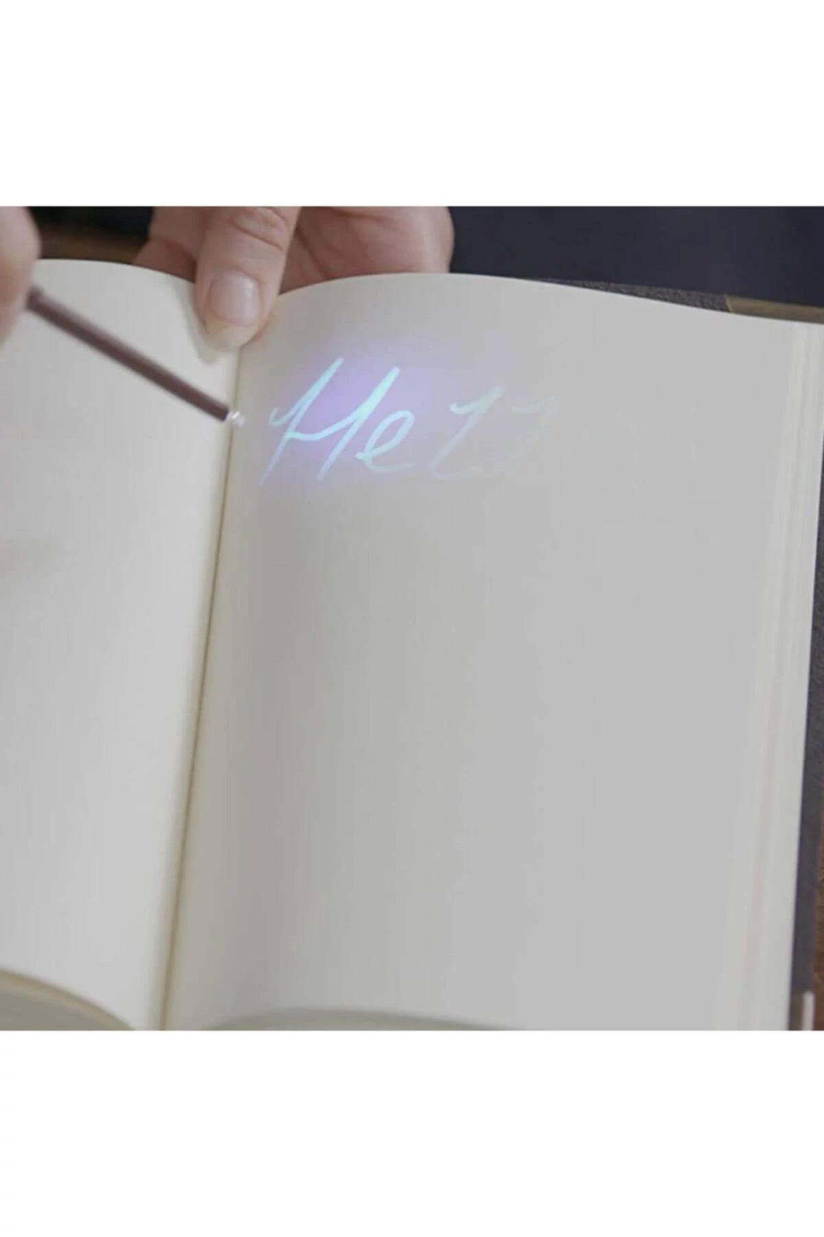 Una mano ilumina tinta invisible en una libreta con un bolígrafo de luz UV.