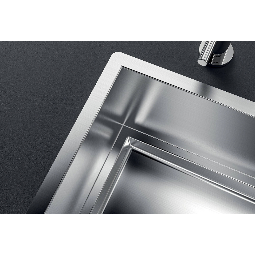 Primo piano di un moderno lavello in acciaio inox su piano di lavoro scuro.