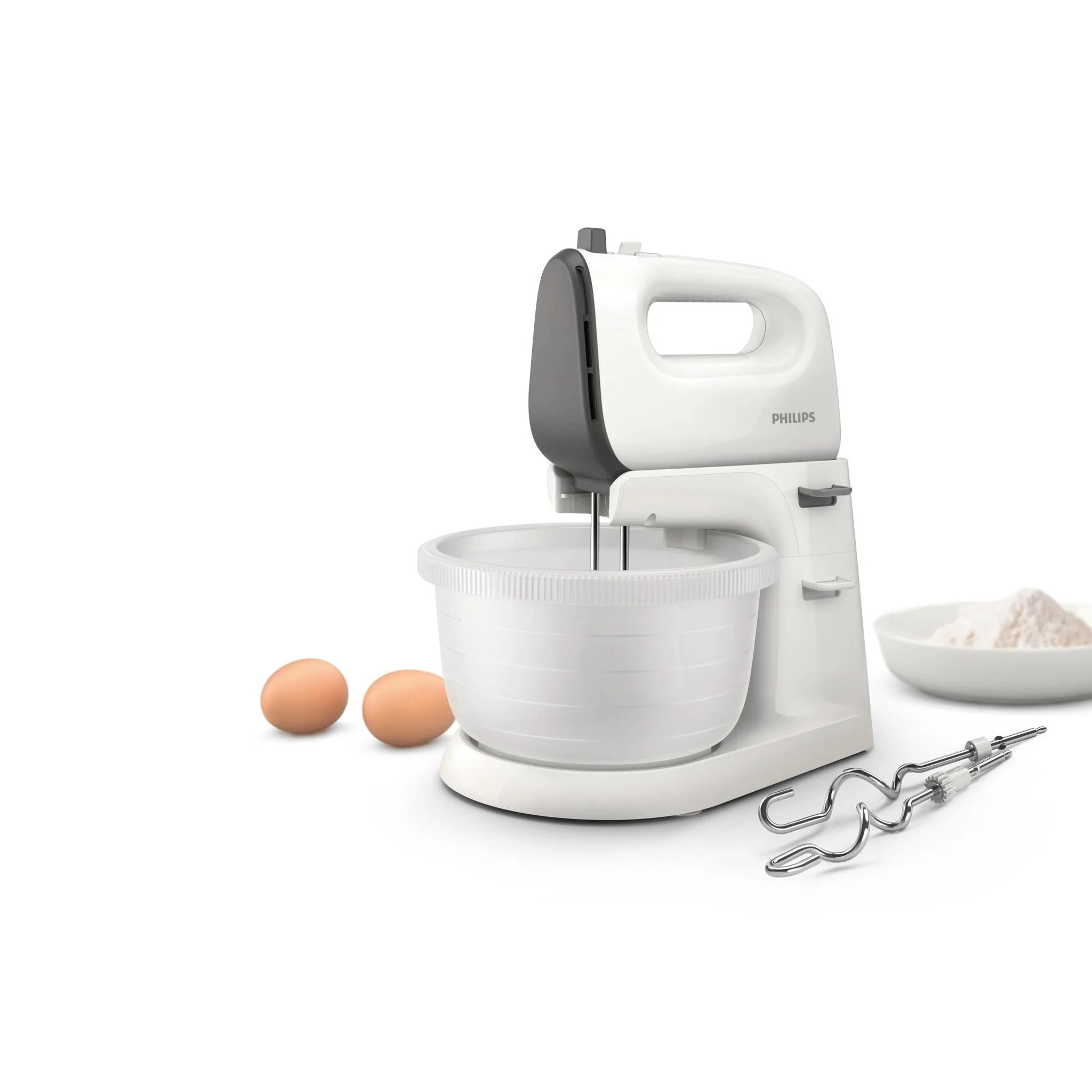 Egy fehér Philips álló mixer fehér alapon, két tojással, liszttel és keverővel.