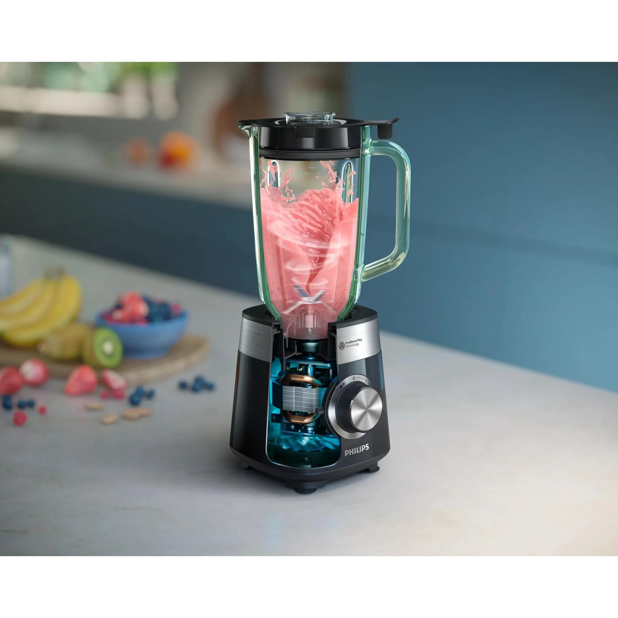 Tezgahtaki bir Philips blender pembe bir smoothie karıştırıyor, arka planda görünür motor ve taze meyveler var.