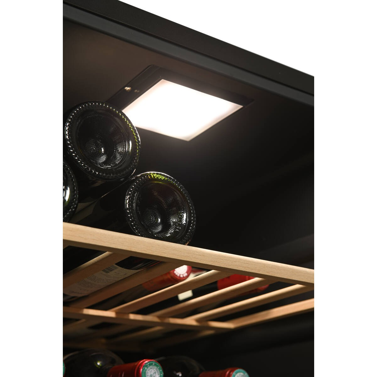 Estante de madera para vinos con botellas en un enfriador oscuro, iluminado desde arriba.
