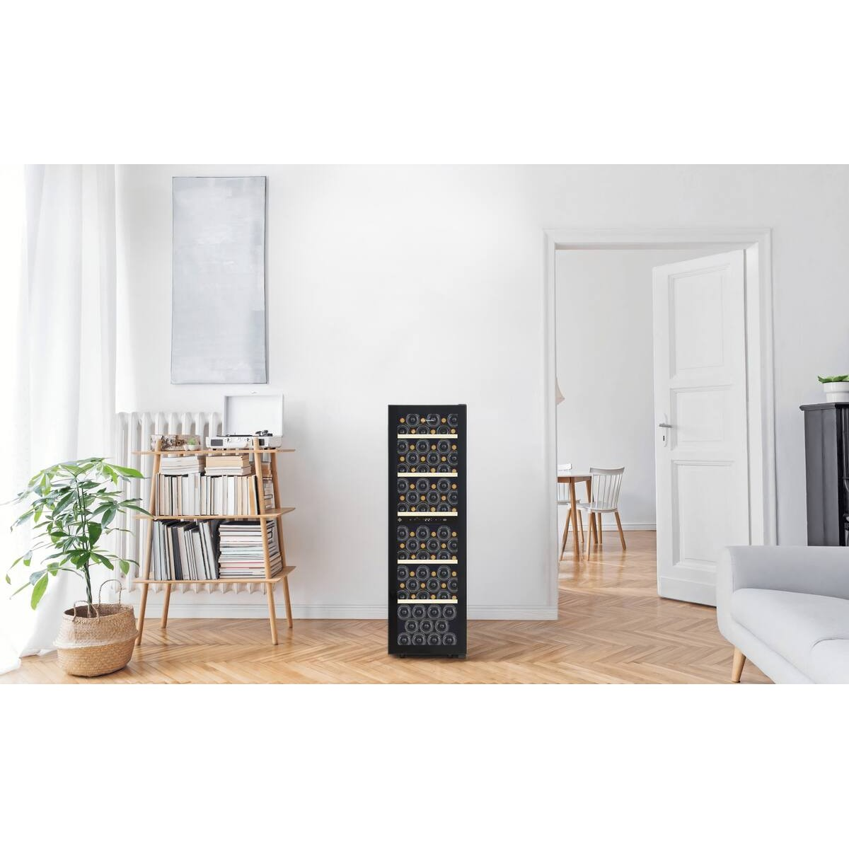 Un elegante refrigerador de vinos negro se encuentra en una sala luminosa con piso de parquet.