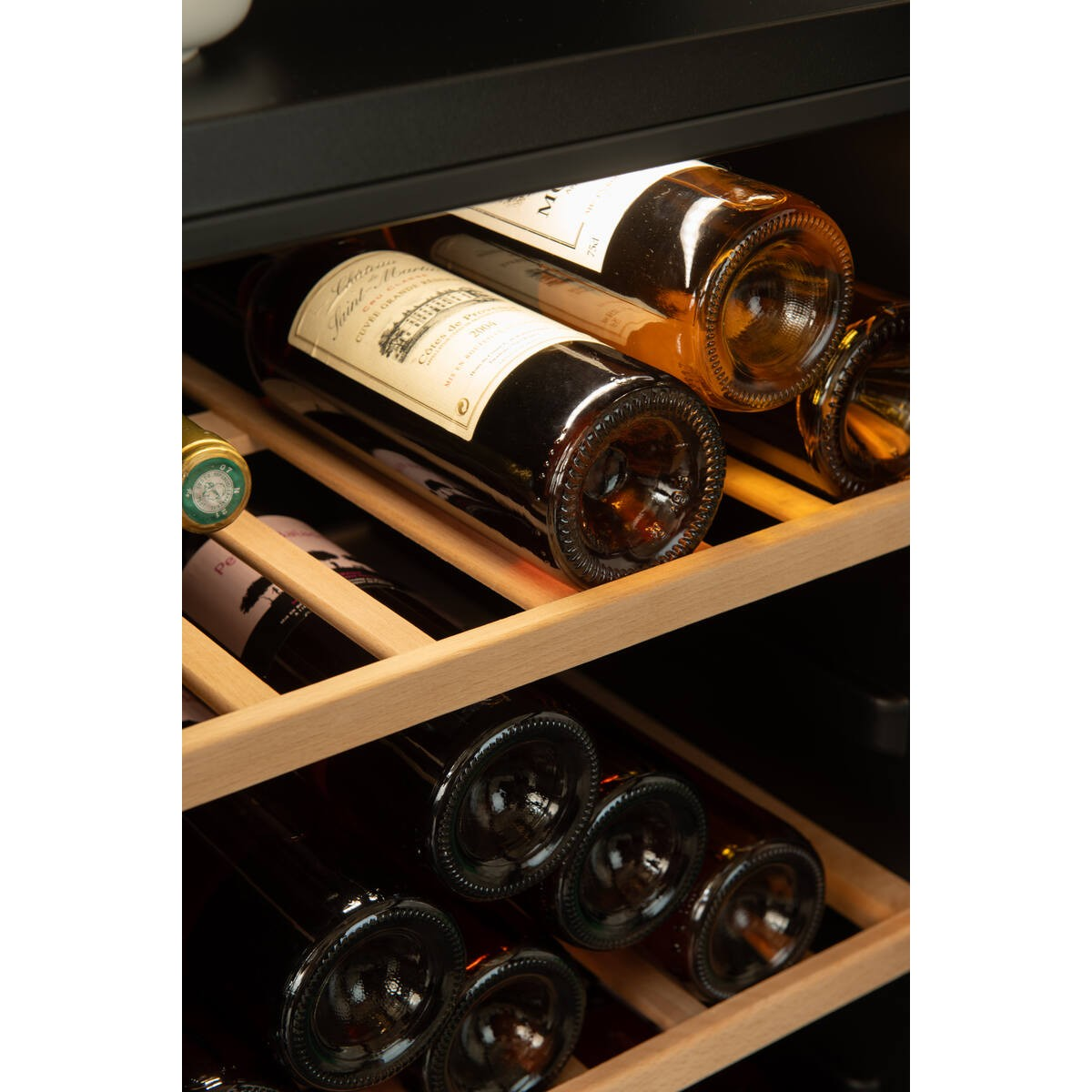 Botellas de vino almacenadas ordenadamente en estantes de madera dentro de una vinoteca iluminada.
