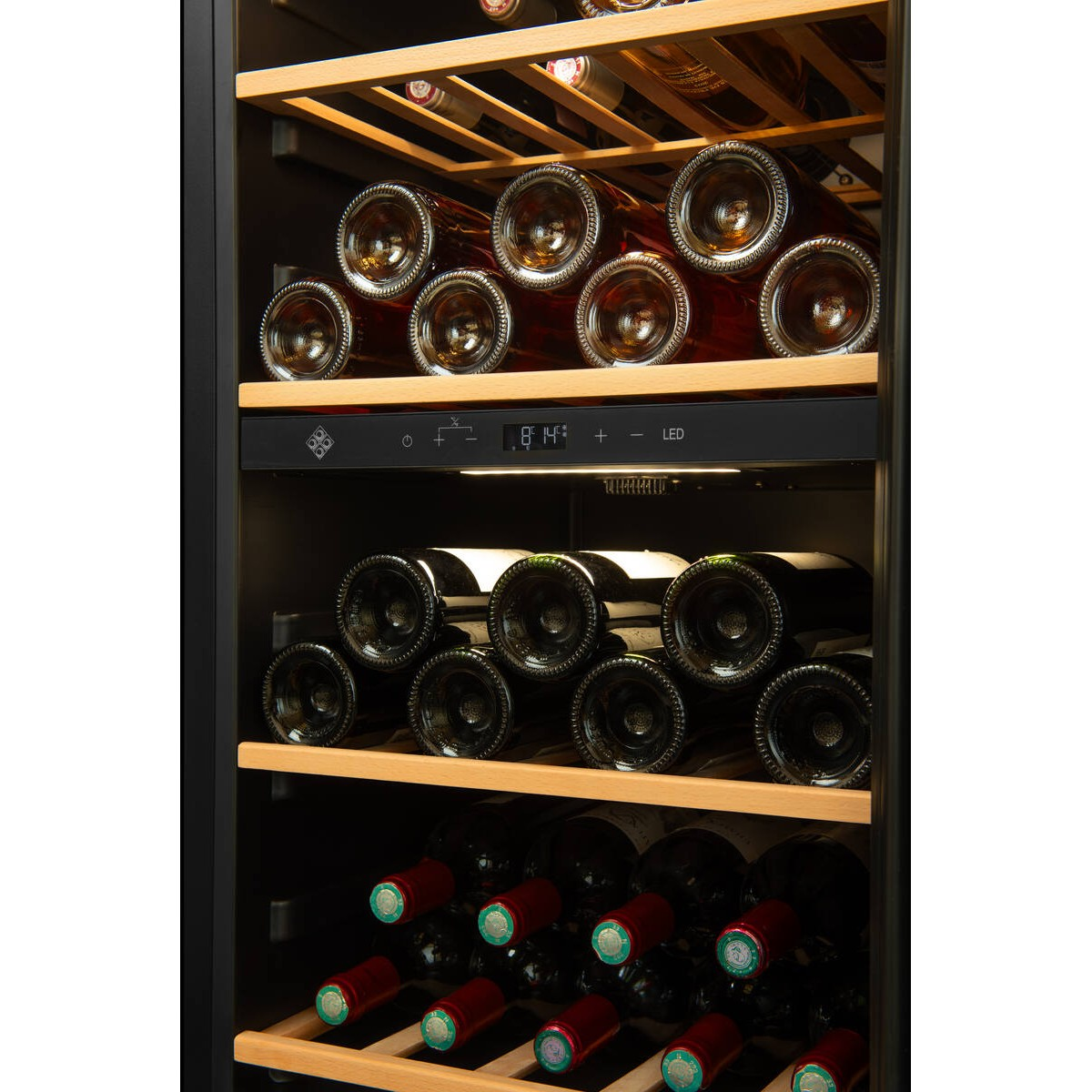 Una vinoteca iluminada con estantes de madera llena de varias botellas de vino.