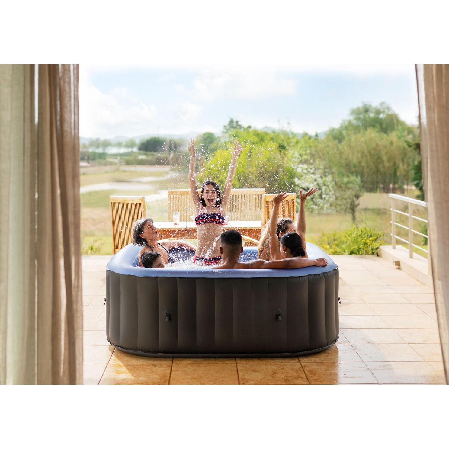 Un grupo de amigos se divierte salpicando agua en un jacuzzi inflable en una terraza.