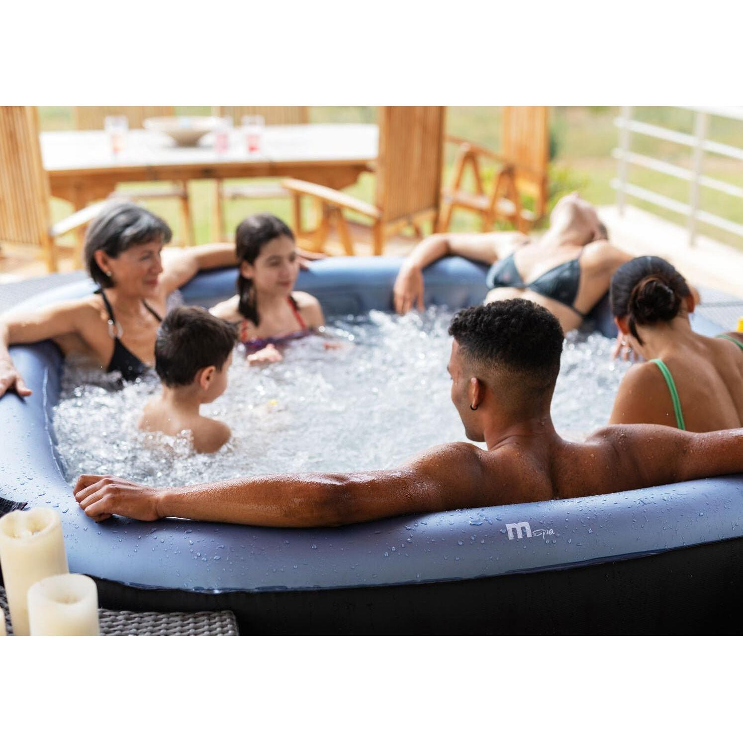 Una familia relajándose junta en un jacuzzi azul inflable al aire libre.