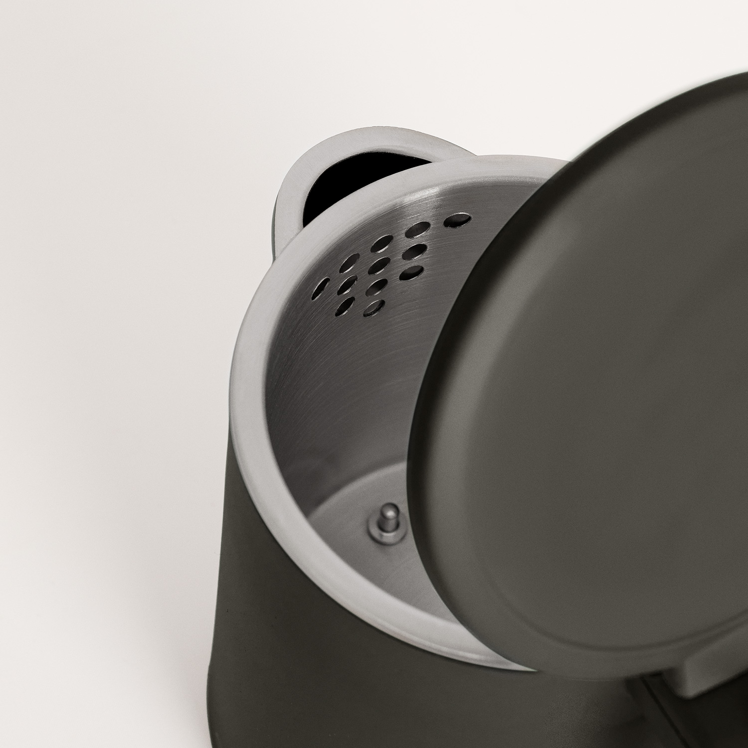 Un hervidor eléctrico gris abierto muestra el interior con un filtro de acero inoxidable incorporado.