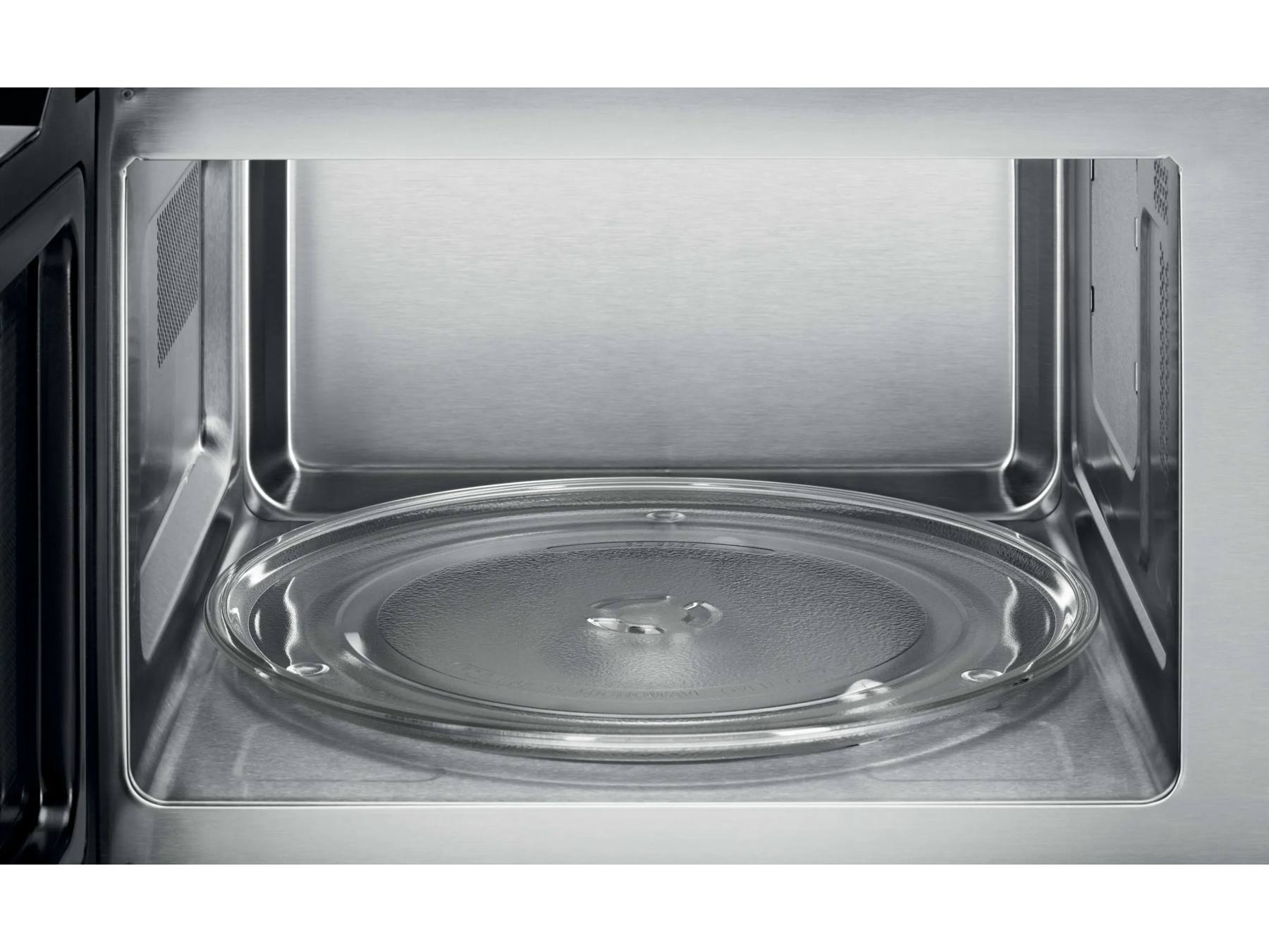 Vista interior de un microondas de acero inoxidable vacío con plato de vidrio.