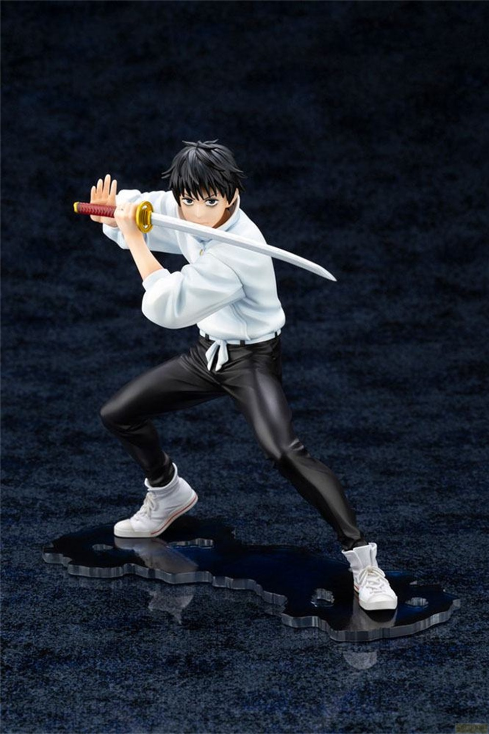 Eine Anime-Figur in Kampfhaltung, mit einem Katana, weißem Hemd und schwarzer Hose auf dunklem Sockel.