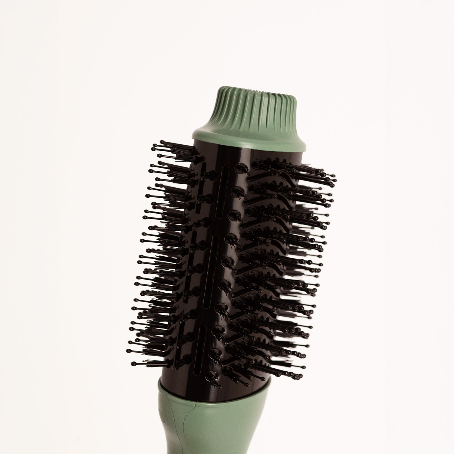 Un cepillo de pelo con cabeza cilíndrica negra, muchas cerdas y extremos verde menta sobre un fondo blanco.