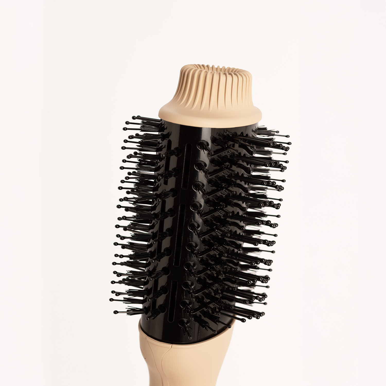 Un cepillo redondo negro para el cabello con detalles en beis sobre fondo blanco.