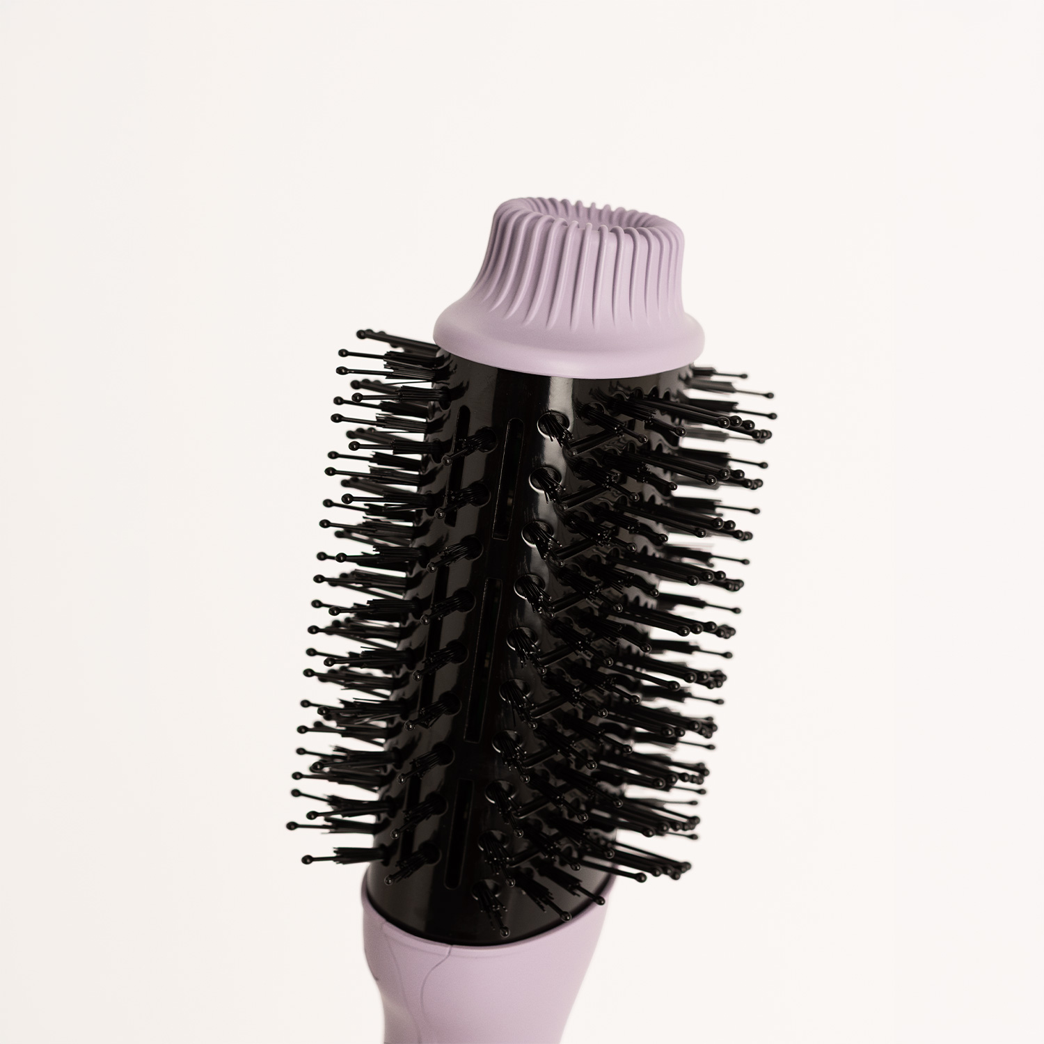 Un cepillo de pelo negro con detalles morados y cerdas finas sobre fondo claro.