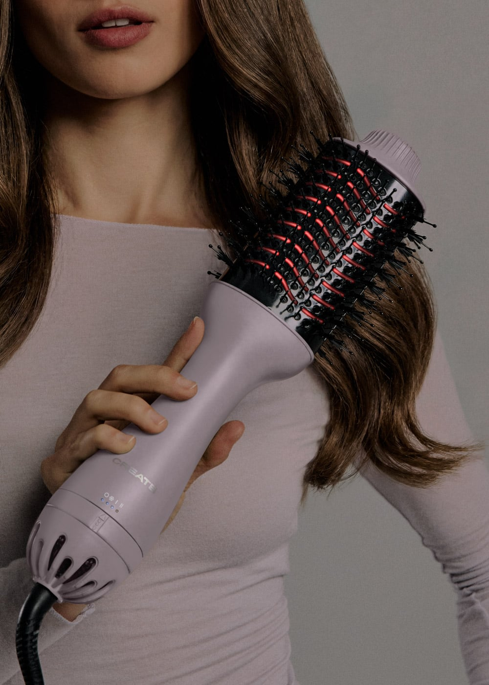 Una mujer sostiene un cepillo secador de pelo lavanda cerca de su cabello.