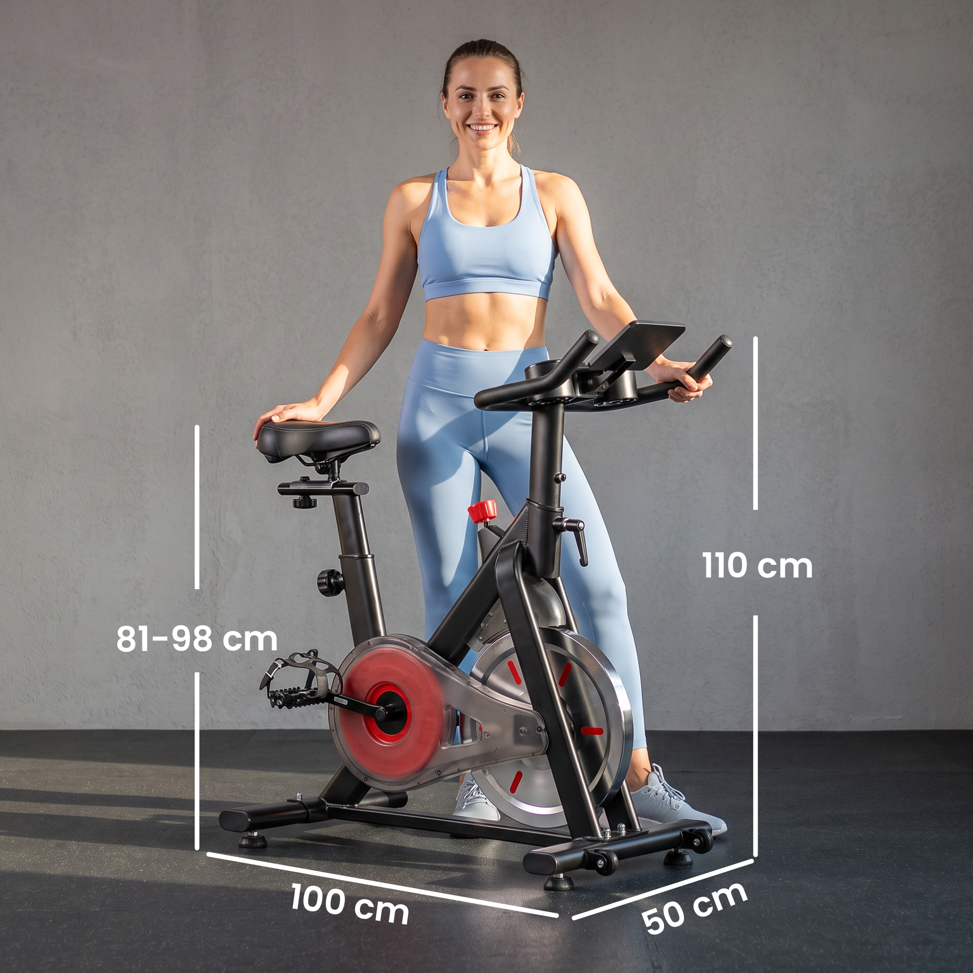 Una mujer en ropa deportiva posa con una bicicleta estática, se muestran las dimensiones.