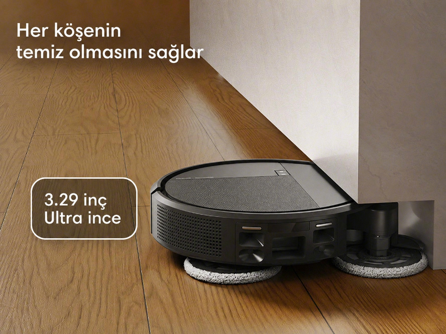 Ahşap zeminde duvar dibini temizleyen siyah robot süpürge.
