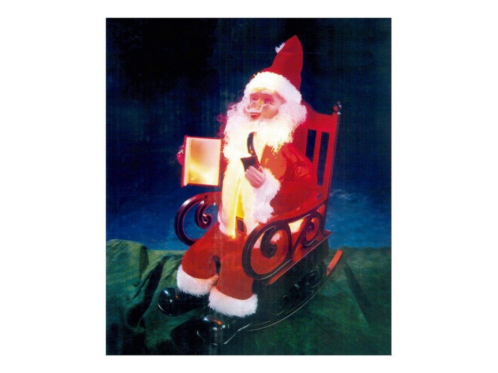 Papá Noel se sienta en una mecedora roja con fondo azul oscuro y sostiene un libro iluminado.