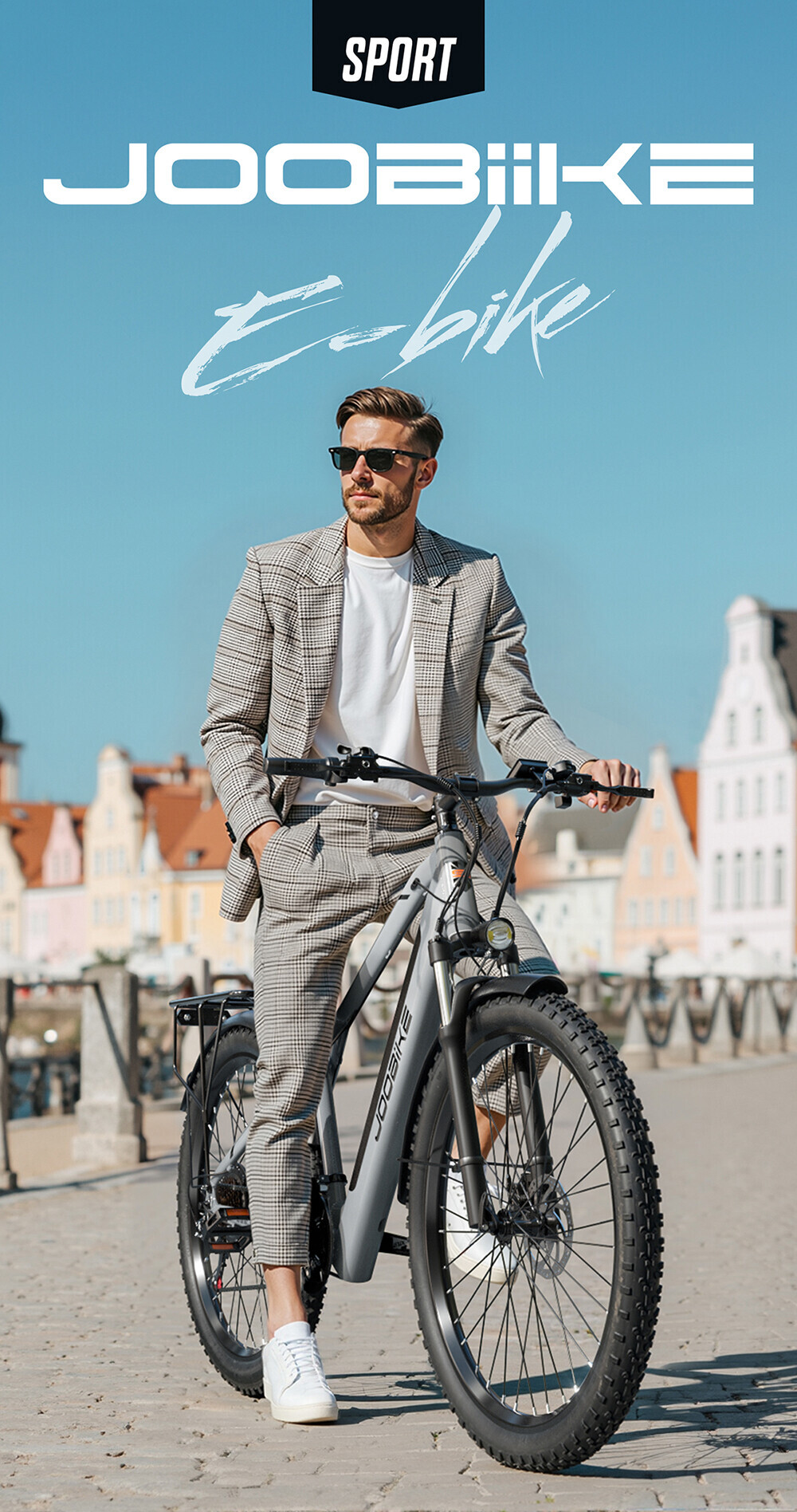 Ein stilvoller Mann im Karoanzug mit Sonnenbrille posiert mit einem modernen E-Bike vor einer Stadtkulisse.