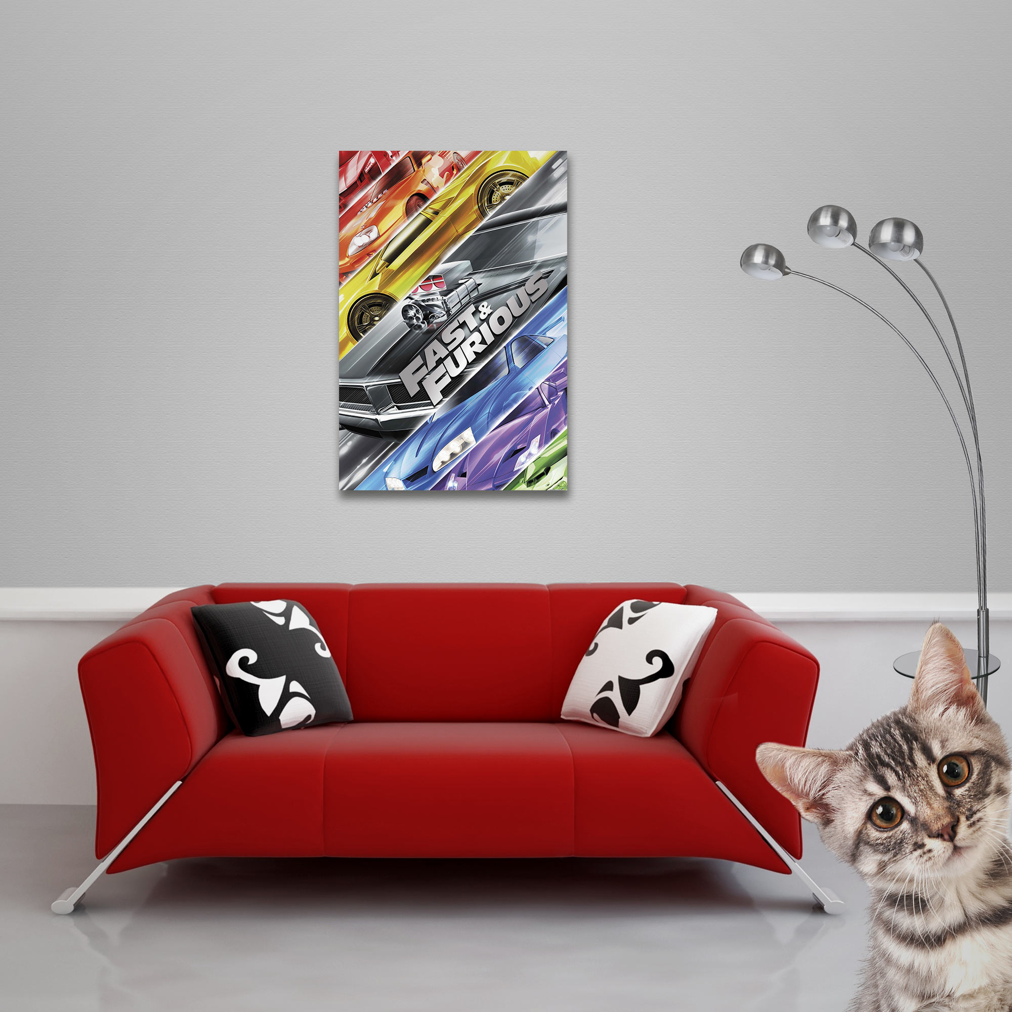Ein rotes Sofa mit Kissen steht vor einer grauen Wand mit einem Fast & Furious Bild und einer Stehlampe; eine Katze blickt hervor.