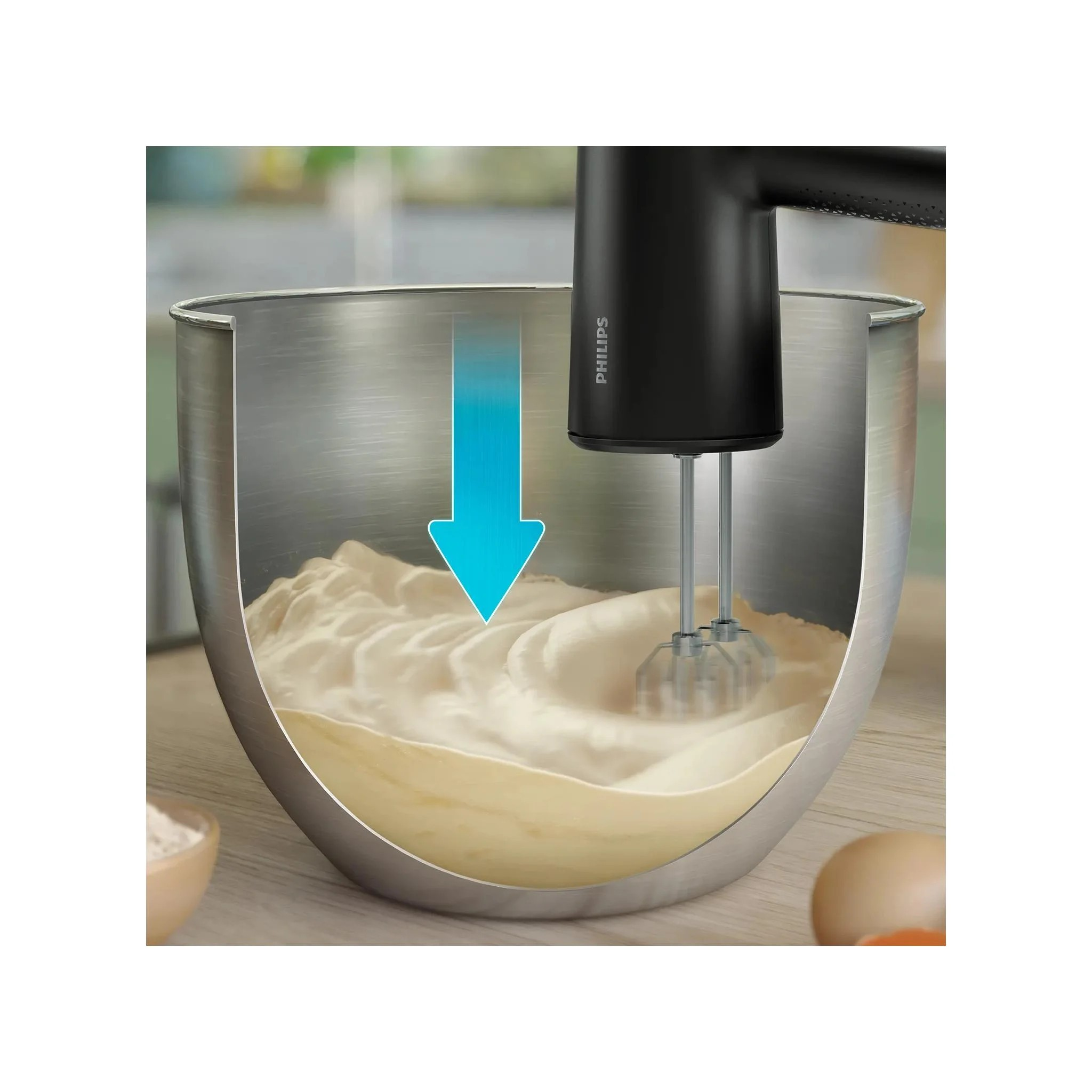 Egy fekete Philips kézi mixer tésztát kever egy nagy fémtálban egy fa munkalapon.