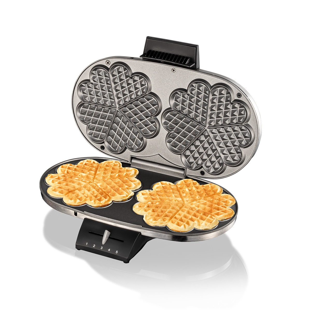 Ein offenes doppeltes Waffeleisen auf weißem Grund zeigt zwei frisch gebackene Waffeln in Herzform.