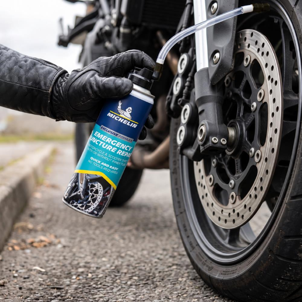 Eldivenli bir el, motosiklet lastik supabına Michelin acil durum lastik tamir spreyi sıkıyor.