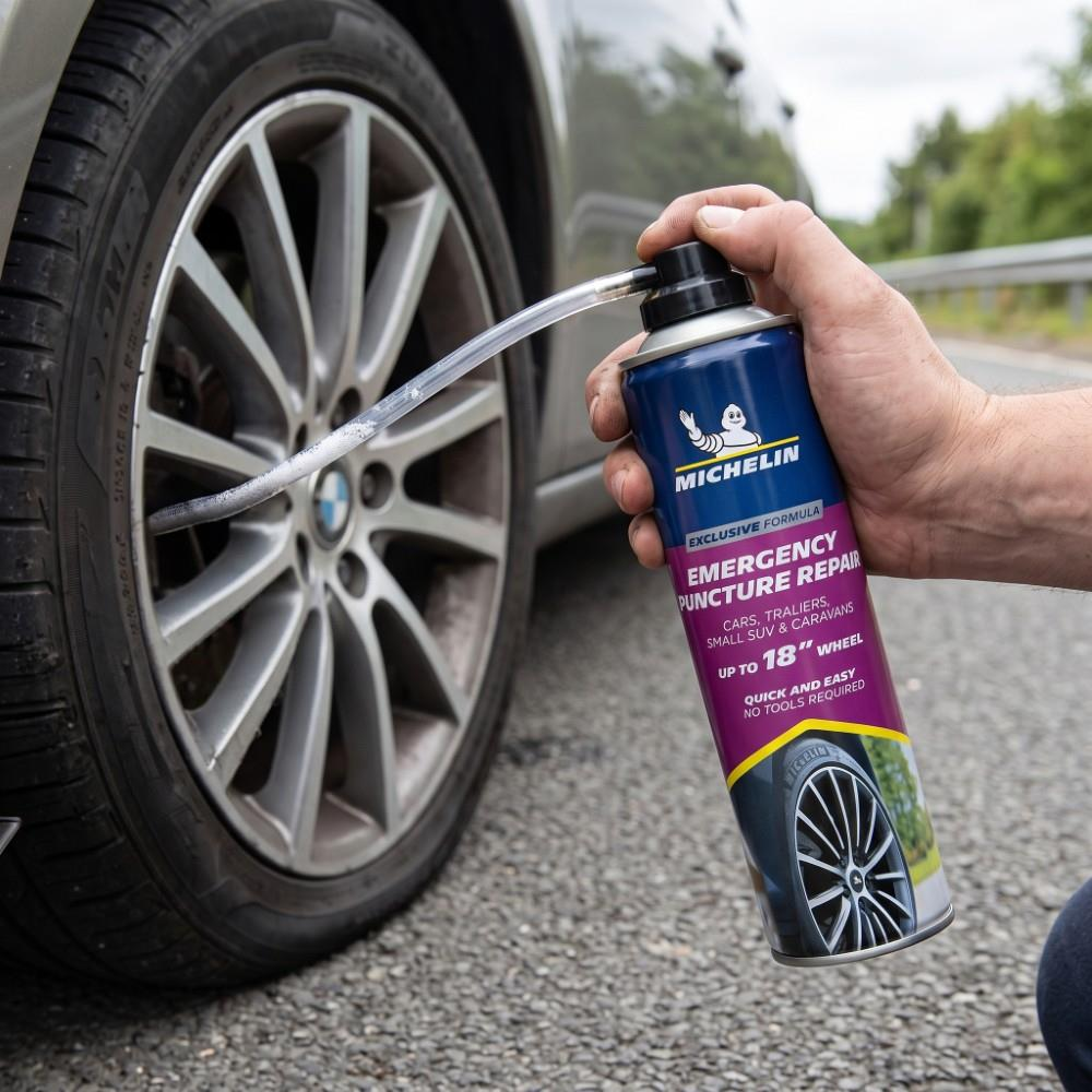 Bir el, araba lastiğini onarmak için hortum kullanan bir Michelin lastik tamir spreyi tutuyor.
