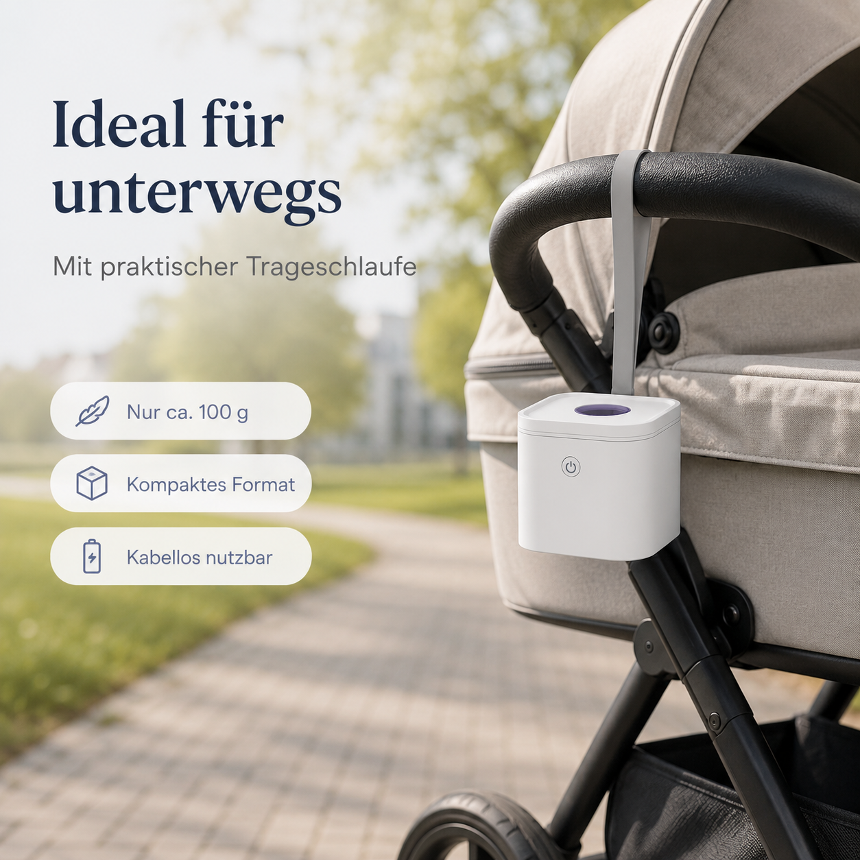 Ein weißes Gerät hängt an einer Trageschlaufe am Griff eines Kinderwagens im Park.