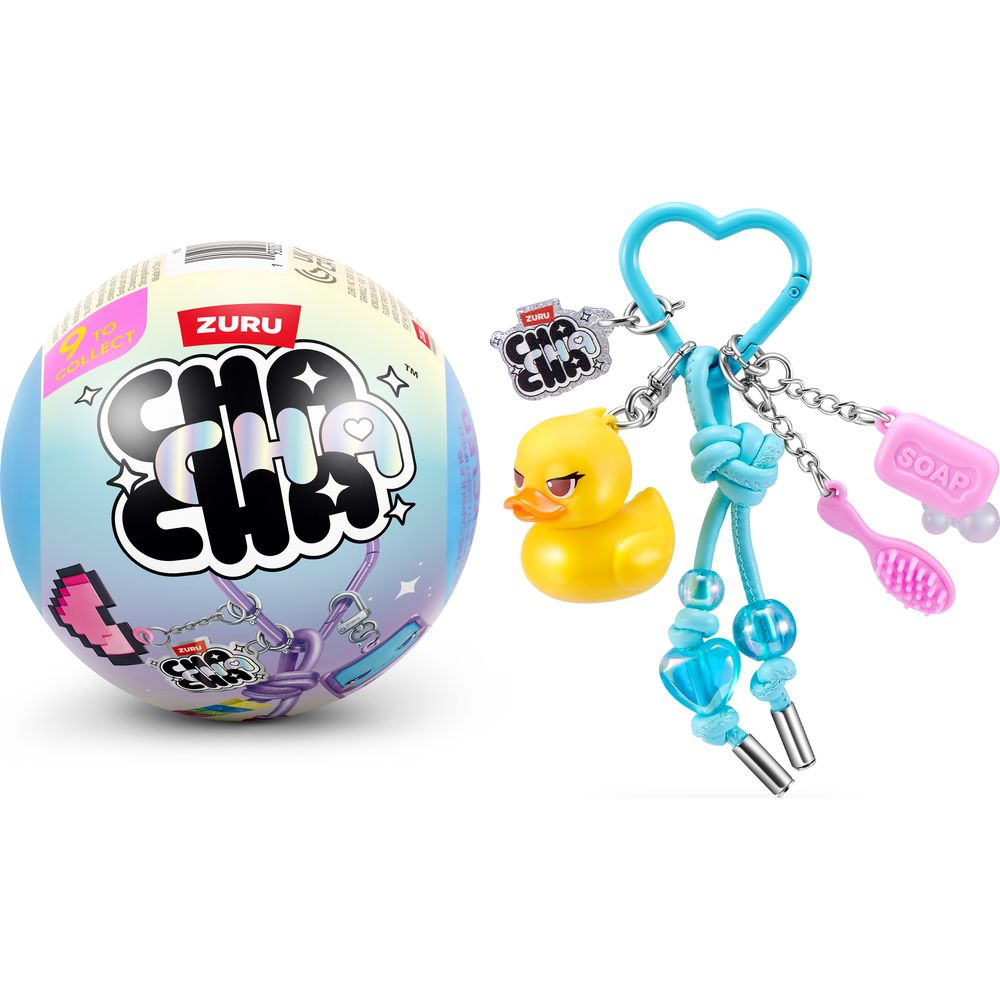 Una cápsula Zuru Cha Cha y un llavero de corazón azul con patito amarillo, cepillo y jabón sobre fondo blanco.