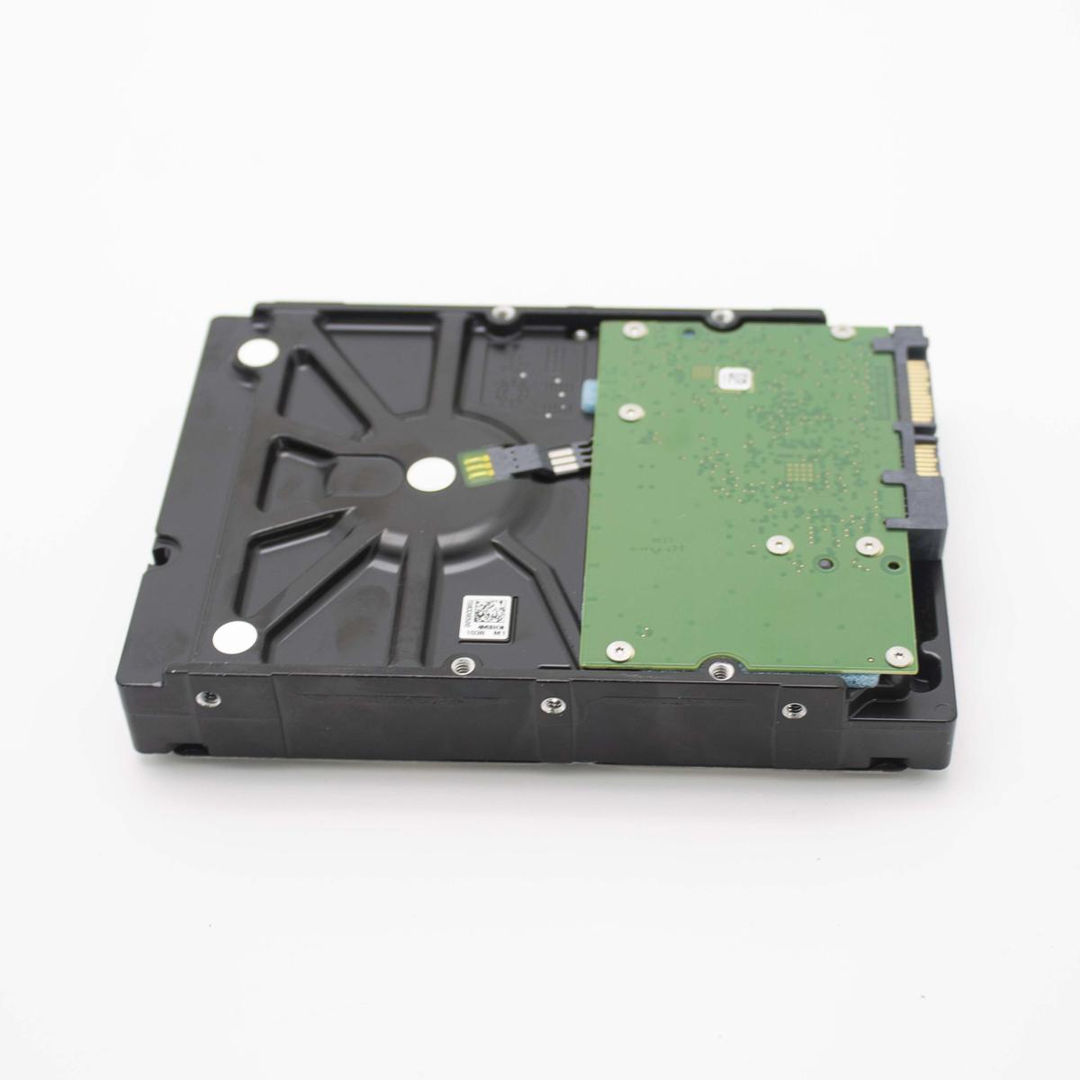 Lato inferiore di un hard disk interno nero con una scheda di circuito verde su sfondo bianco.