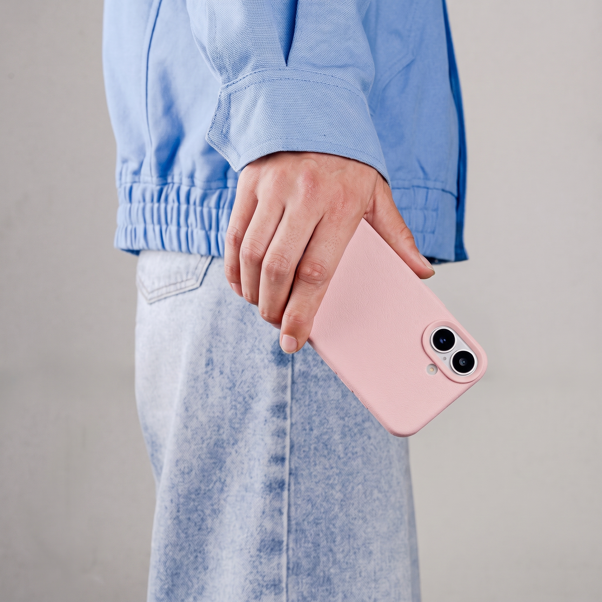 Een hand houdt een roze smartphone vast met twee cameralenzen.