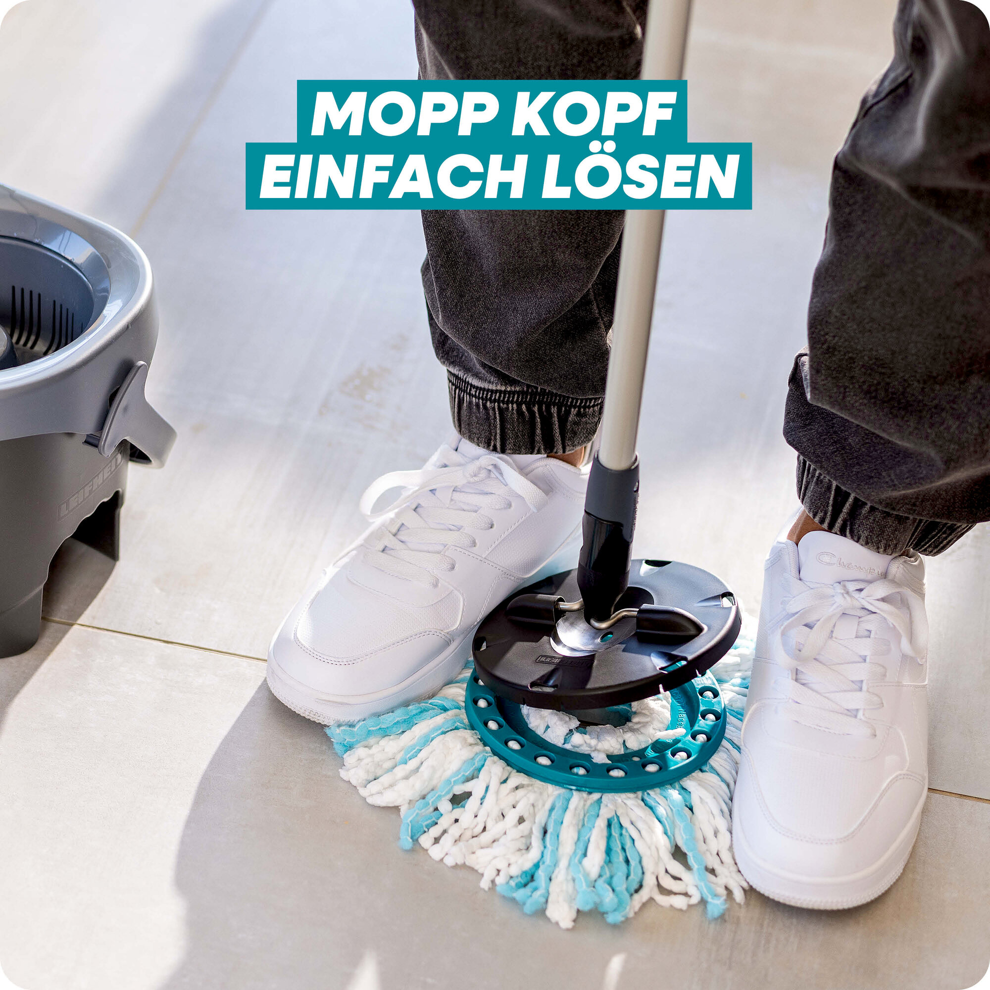 Person in weißem Sneakern steht auf Fliesenboden neben einem Mopp und Eimer.