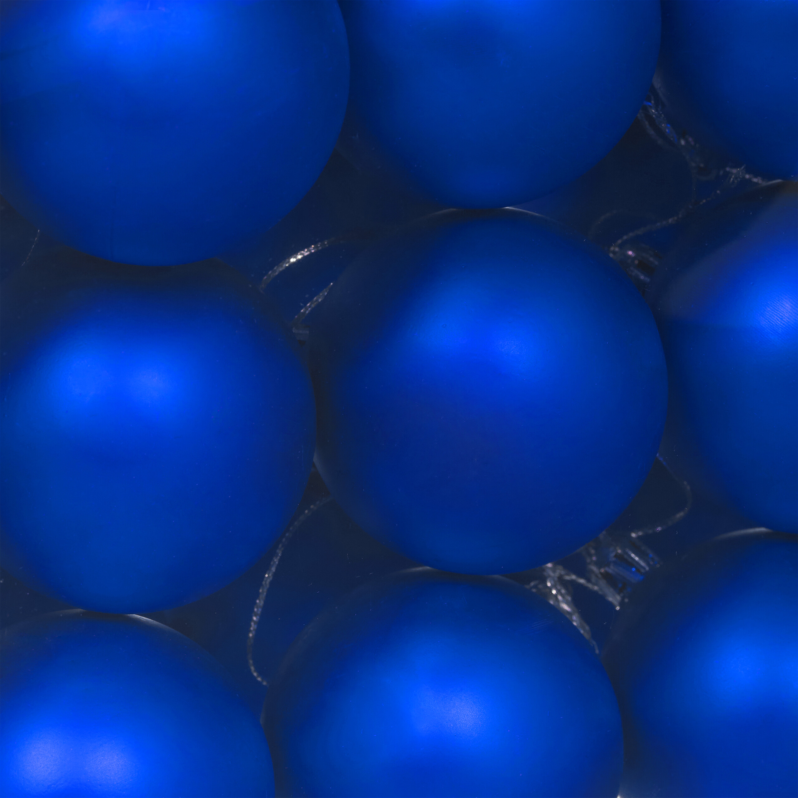 Eine Nahaufnahme glänzender blauer Weihnachtskugeln, die das Bild ausfüllen.