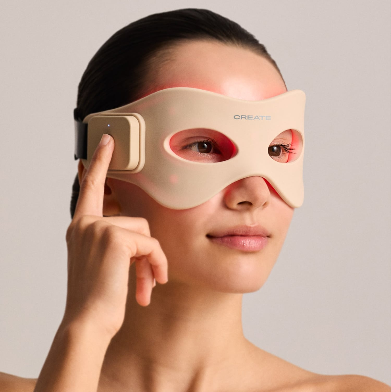 Una mujer lleva una mascarilla facial LED beige con luces rojas y presiona el botón.