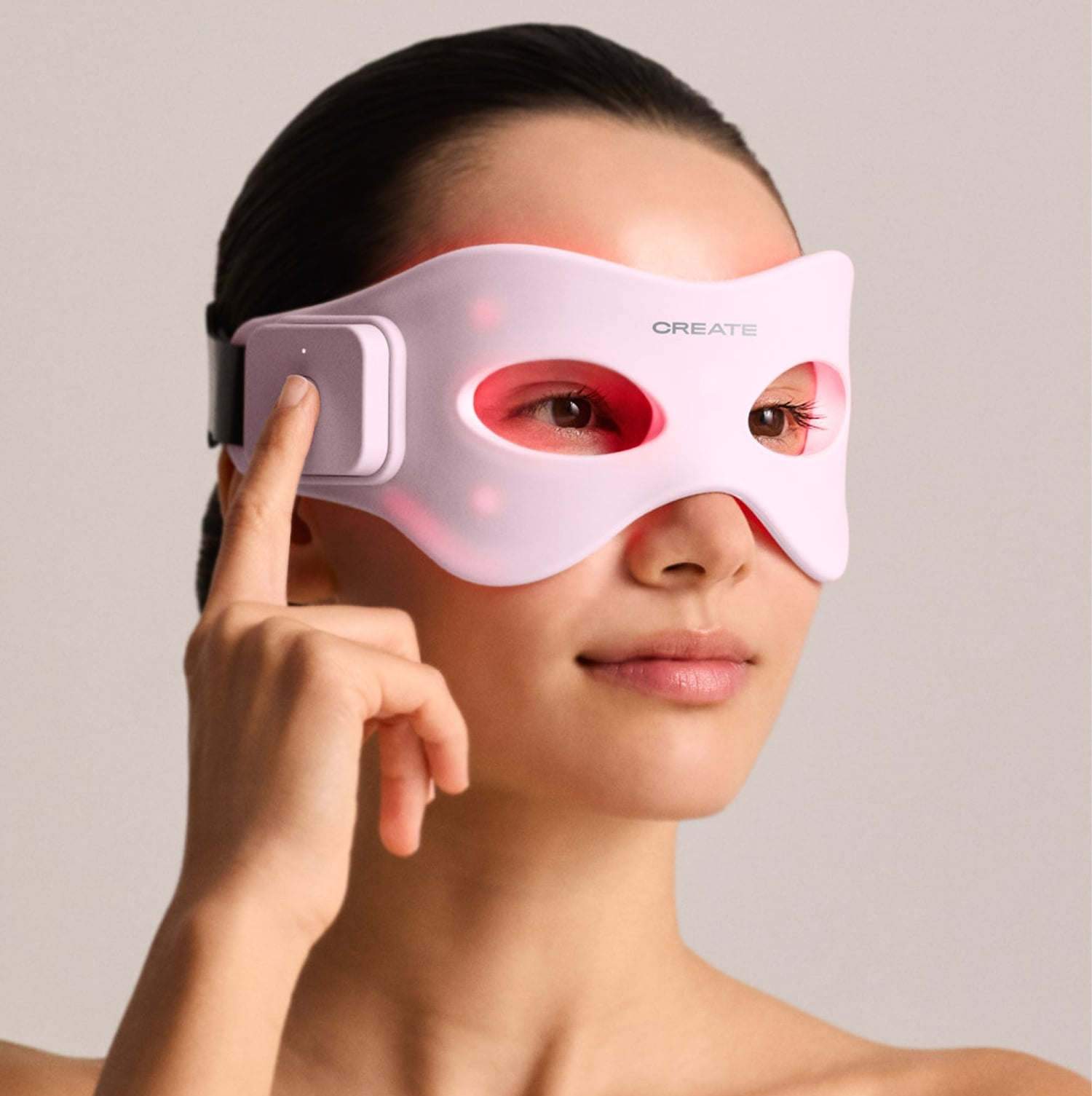 Una mujer lleva una mascarilla facial LED rosa con luz roja alrededor de los ojos.
