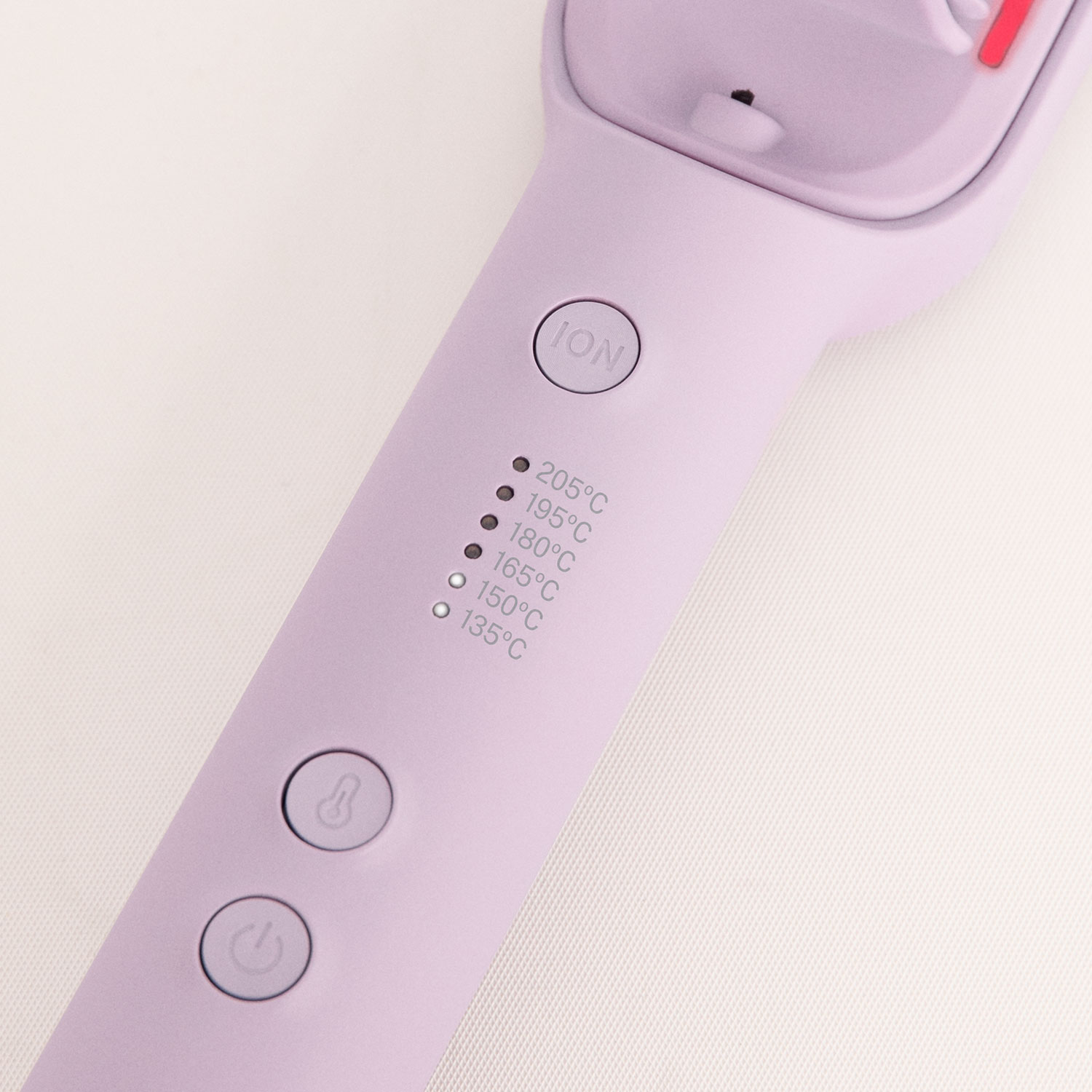 Dispositivo de peinado lila con botón ION, indicadores de temperatura y botón de encendido sobre fondo claro.